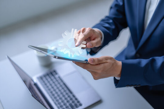 Businessperson using tablet computer with digital gear interface - Powered by Adobe