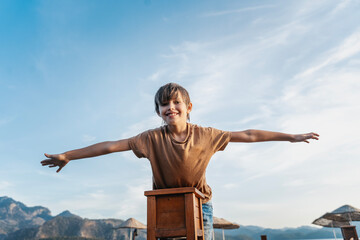 Portrait of carefree smiling Caucasian boy on sea pier during summer vacation at sea