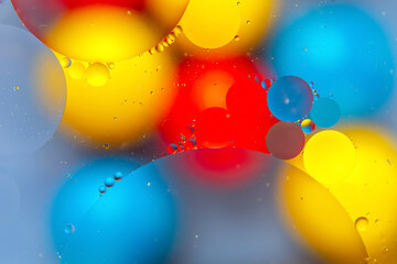 Vibrant water droplets on a colorful surface with red, yellow, blue, and green hues, creating an...