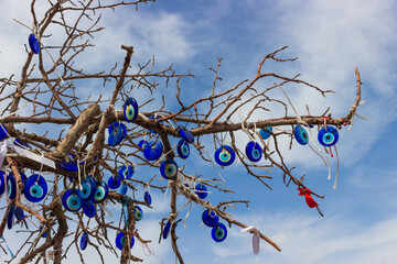 Blue Evil Eye pendants and ribbons in Wish tree against blue sky background in Uchisar in Cappadocia, Turkey. Many evil eye amulet are tied to dry wood.