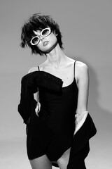 stylish woman posing in black dress and sunglasses with short hair in black and white artistic...