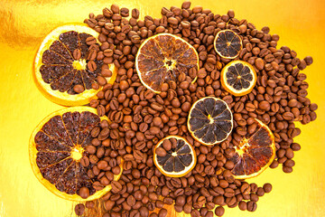 Dried orange slices rest atop a pile of roasted coffee beans on a golden surface, blending citrus...
