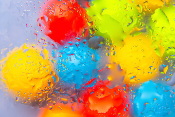 Vibrant abstract composition of water drops in red, yellow, blue, and green hues on a glossy...