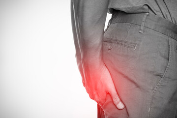 Man clutching buttocks in pain with red spot highlight, concept of hemorrhoids or anal discomfort,...