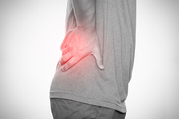 Man suffering from lower back pain, holding waist with red highlight, isolated on white background.