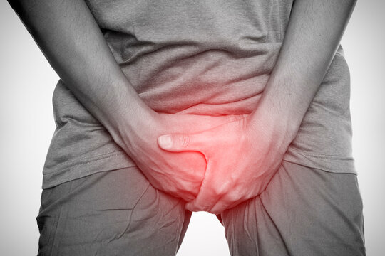 Man clutching groin area in pain with red highlight, indicating genital discomfort or urological problem, isolated on white background.