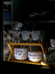 Elegant Floral Ceramic Cups and Bowls in Display Window
