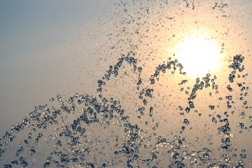 silhouettes of drops falling water fountain against the backdrop of the setting sun