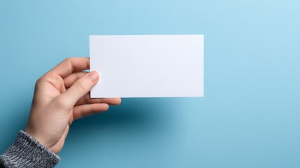 Fototapeta premium Hand holding a white blank sign on a light blue background, a concept of political protest or picket .