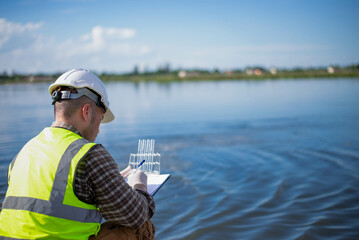 A specialist engineer at a treatment pond is checking the water quality of the treated pond.