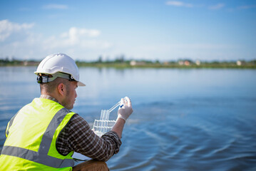 A specialist engineer at a treatment pond is checking the water quality of the treated pond.