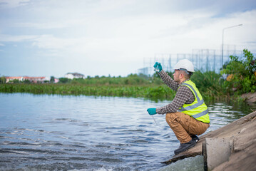 An environmental expert is collecting water samples from a treatment pond to be taken back to the lab for testing of its cleanliness.