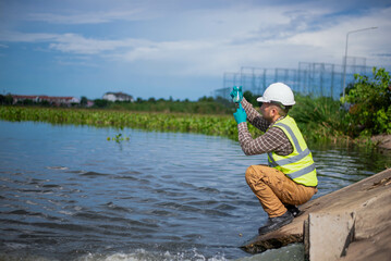 An environmental expert is collecting water samples from a treatment pond to be taken back to the...