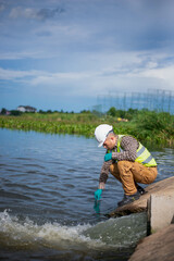 An environmental expert is collecting water samples from a treatment pond to be taken back to the...