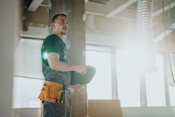 Construction worker wearing protective gear and carrying tools, engaged in a building renovation...