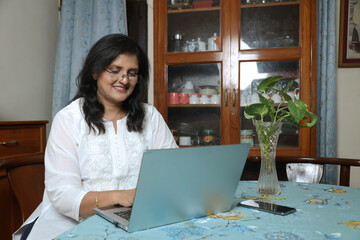 Indian woman freelancer working on laptop at home. Beautiful young woman in casual clothing using...