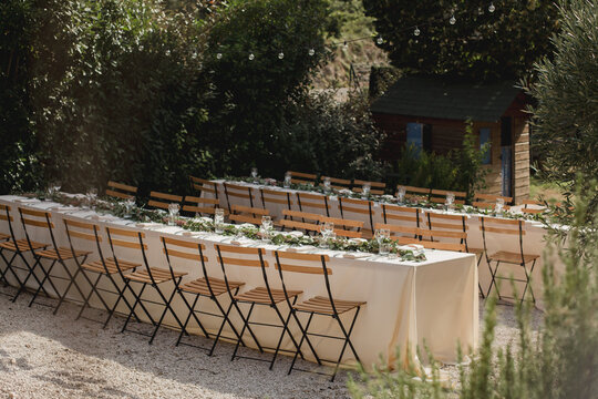 Overview of long banquet tables with string lights in a garden setting. Wedding banquet table.