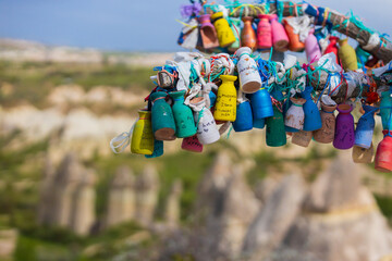 Colors clay love jugs with names of lovers and wishes in Wish tree against blurred landscape of Love Valley in Cappadocia, Turkey. Background with copy space