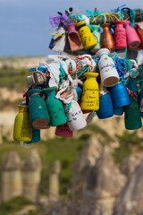 Many colorful clay love pots with names of lovers and wishes are tied to Wish tree against blurred landscape of Love Valley in Cappadocia, Turkey.