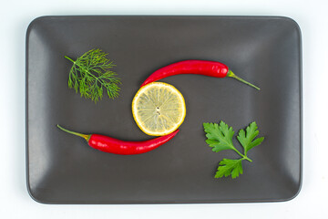 Red hot pepper with lemon on a gray plate. Healthy vegetable food and vitamins