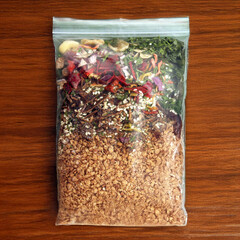 A sealed plastic bag filled with a colorful mix of dehydrated vegetables, herbs, and grains,...
