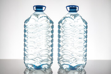 Two large plastic water bottles with blue caps and textured design, standing side by side on a white background. Perfect for hydration, health, and eco-friendly themes.