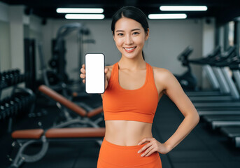 Smiling Asian Woman in Sportswear Holding a Blank Smartphone Mockup at the Gym