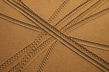 Abstract intersecting tire tracks in brown sand, aerial texture for backgrounds