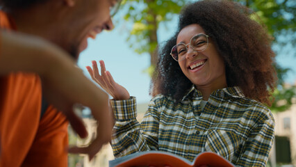 Two students African American woman girl talking laughing happy funny communicate conversation with guy man discuss homework copybook studying education task together male with female learning in city