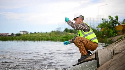 An environmental expert is collecting water samples from a treatment pond to be taken back to the lab for testing of its cleanliness.