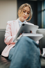 A determined individual in smart attire sitting on a couch, analyzing important information on a...