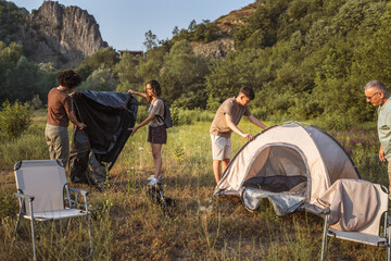 Fototapeta premium happy caucasian family prepare camping together and install tent