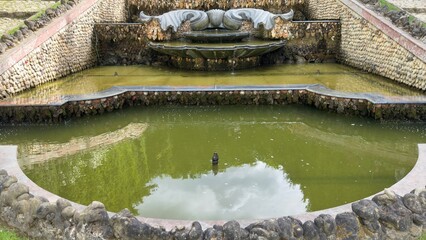 Multi-Tiered Stone Fountain with Sculptures and Green Water