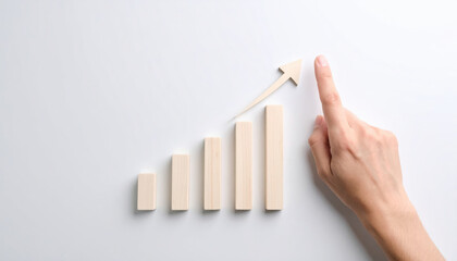 Hand pointing to rising bar chart with arrow symbolizing growth and success