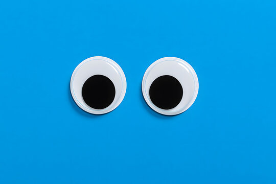 Pair of plastic googly eyes on vibrant blue background, playful craft supplies concept, minimal composition with cartoon expression, creative hobby elements, isolated fun eyes for design humor project