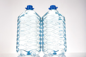 Two plastic water bottles with blue lids and a unique wavy design, isolated on a white background....
