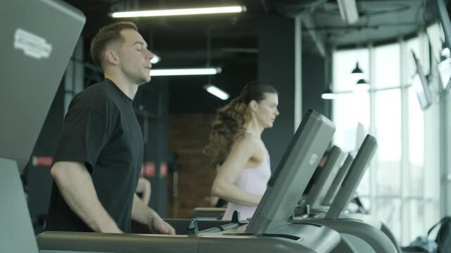 Man and woman doing fitness exercises in gym. Strength, endurance and training focus in modern fitness center