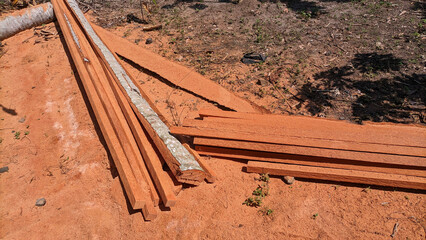 A pile of wooden planks from cutting coconut tree trunks in an open area, showing the initial...