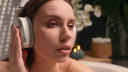 Caucasian female woman girl closed eyes listening music in waterproof headphones enjoying morning beauty procedure smooth skin at home bathroom relaxing listen audio melody song stress relief weekend