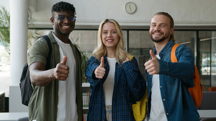 Closeup three multiracial friends diversity students smiling showing thumbs up likes recommend...