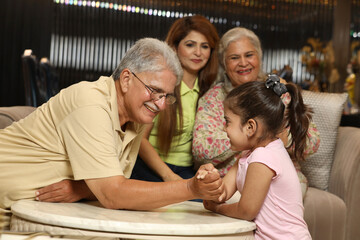 Indian happy family playing arm wrestle game at living room. Concept : Happy Family Lifestyle theme.