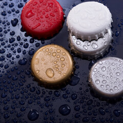 Background with bottle caps with water drops on blue background close up