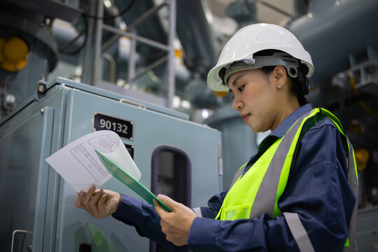 Female substation engineer inspects gas insulated switchgear with focus and care in industrial electrical environment ensuring safety and operational efficiency
