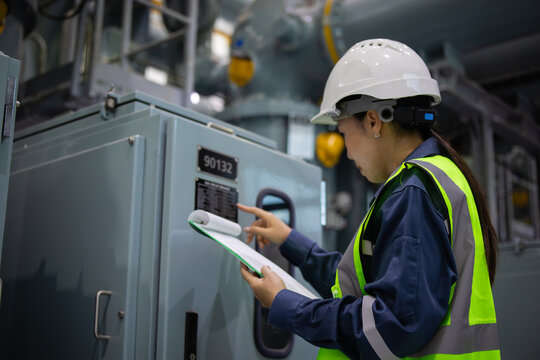 Substation engineer inspects gas insulated switchgear equipment carefully while holding clipboard in industrial environment ensuring safety and operational standards