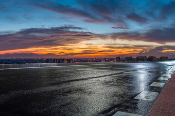 Wet asphalt road and city skyline with beautiful sky clouds at night