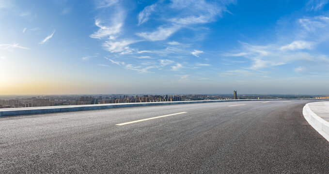 Empty asphalt highway road and city skyline with residential area buildings under blue sky