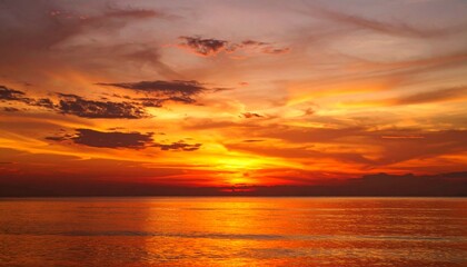 Fototapeta premium Deep crimson glow washes across the sky, reflecting on a smooth surface below with rich amber gradients and fading edges. 