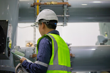 Substation engineer inspects gas insulated switchgear equipment carefully wearing safety helmet and...