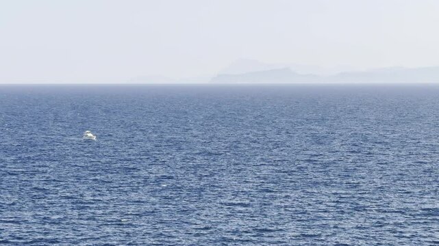 White boat in the sea against the background of blue open sky and mountains
