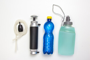 A set of outdoor water purification tools on a white background, including a black pump with a...